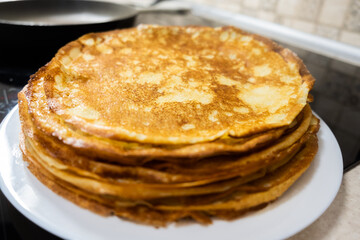 a stack of pancakes on a white plate on a kitchen background