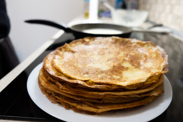 a stack of pancakes on a white plate on a kitchen background