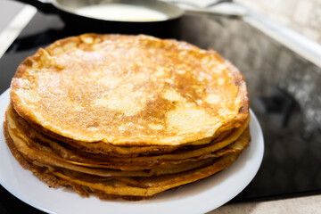 a stack of pancakes on a white plate on a kitchen background