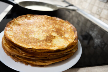a stack of pancakes on a white plate on a kitchen background