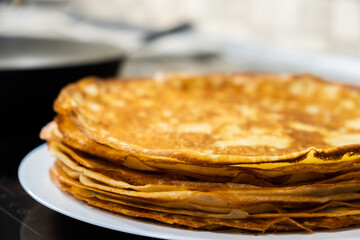 a stack of pancakes on a white plate on a kitchen background