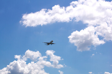 Passenger airplane in a blue sky with clouds - 414557938