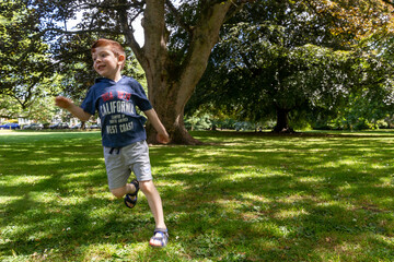 A boy running in a park in summer