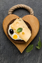 Open  faced cheese sandwich canape or crostini on a wooden serving board  on dark stone background closeup. Top view.