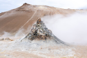Iceland, Lake Myvatn District, Hverir Geothermal Area. Numerous thermal vents sitting next to a hill of reddish lava.