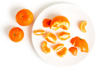 Peeling Tangerines or Clementines in White Plate, isolated on white background