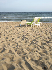 Vertical image of a sandy beach with two beach chairs looking at the sea.Texture of the sand,copy space, text space,web context.