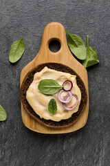 Open faced hummus sandwich canape or crostini on a wooden serving board  on dark stone background closeup. Top view.