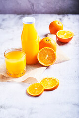 
orange juice in a glass container with some oranges