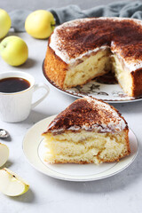 Charlotte with apples and a cup of coffee on a light background. A cut piece of charlotte in the foreground. Close-up