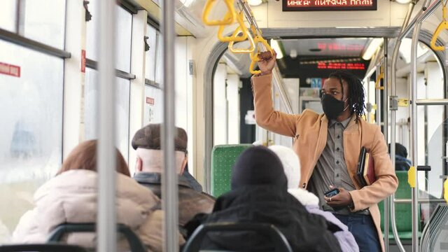Public transport concept. Covid, coronavitus pandemic rules. An African man is going by gus to work wearing mask.