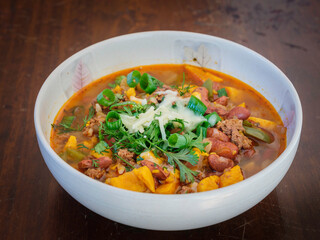Chili with sweet potato, scallion, and cheese on rustic table 