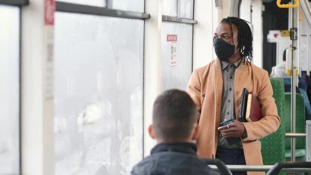 Public transport concept. Covid, coronavitus pandemic rules. An African man is going by gus to work wearing mask.
