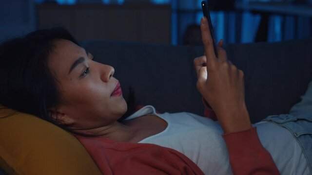 Night time ​addict Asia lady use smartphone sleep in bed at home feel boring and scrolling checking phone see message in online. Stay at house, Self quarantine,  Internet addiction and mobile abuse.