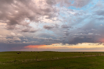Fototapeta premium Sunset theme for sky replacement background with dark themed clouds, blue sky and sun shining on the horizon. Great for tranquil, calm, serene country or rural themed art.