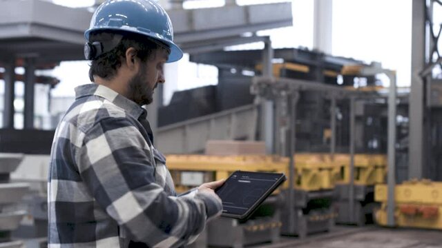 Mann bedient Tablet in smarter Produktionsanlage
