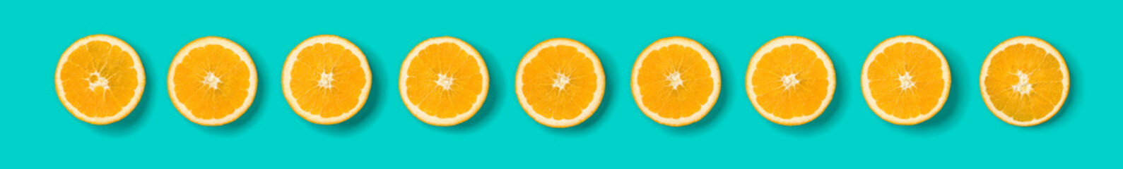 Fruit pattern of orange slices on blue background. Flat lay, top view. Banner, seamless pattern, creative summer food concept.