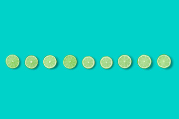 Fruit pattern of lime slices on blue background. Flat lay, top view, creative summer food concept. Minimal style.