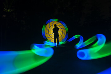 One person standing alone against beautiful color circle LED light painting as the backdrop	