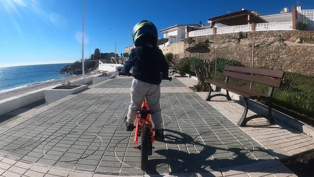 Ni&ntilde;o con tres a&ntilde;os montando en bici con pedales con su casco puesto.