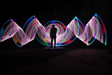 One person standing alone against beautiful color circle LED light painting as the backdrop	