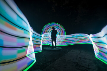 One person standing alone against beautiful color circle LED light painting as the backdrop	