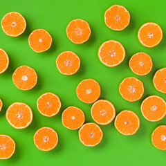 Fruit pattern of fresh orange slices on green background. Flat lay, top view. Pop art design, creative summer concept. Half of citrus in minimal style.