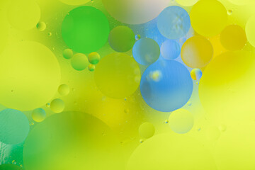 bright colorful oily drops in water with colorful background, close-up 