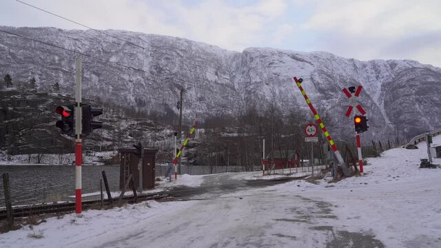 Booms closing down and lights starts flashing to warn about incoming train at level crossing - Warning lights - Snowy weather Norway