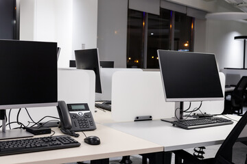 Empty modern office with computers and phone at night