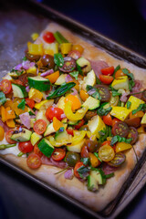 Homemade roasted vegetarian flatbread pizza on a dark sheet pan, top view