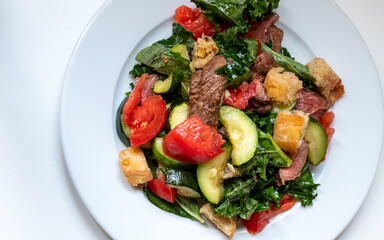 Homemade roasted stake with rustic vegetables of tomato, kale, zucchini, basil, and garlic bread