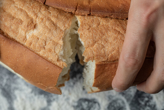 Cloae up photo of FeMale hands breaking freshly baked bread, closeup
