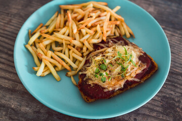 healthy plant-based food, vegan parma with plant-based schnitzel topped with tomato sauce and dairy-free cheese served with a side of chips