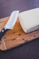 Fototapeta na wymiar simple food ingredients, block of extra firm tofu on cutting board with knife