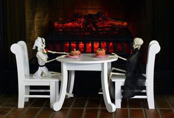 Man and woman skeleton sitting down to dinner of rotting shriveled up pumpkins by fireplace in hell