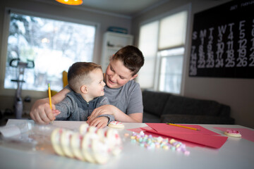 Fototapeta premium boy helping brother write valentine's day notes