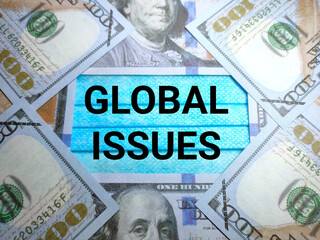 Fototapeta premium Selective focus of text GLOBAL ISSUES on a face mask with banknote.Shot were noise and grain.