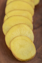 Close up photo of Sliced potato on brown wooden board
