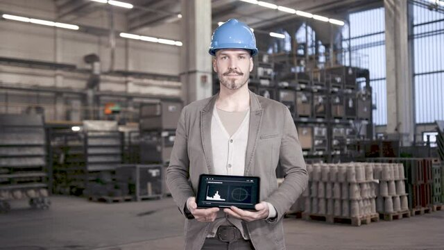 Proud engineer showing big data app on tablet computer in industrial plant