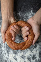 Vertical photo of Woman hands holding fresh Turkish simit on board