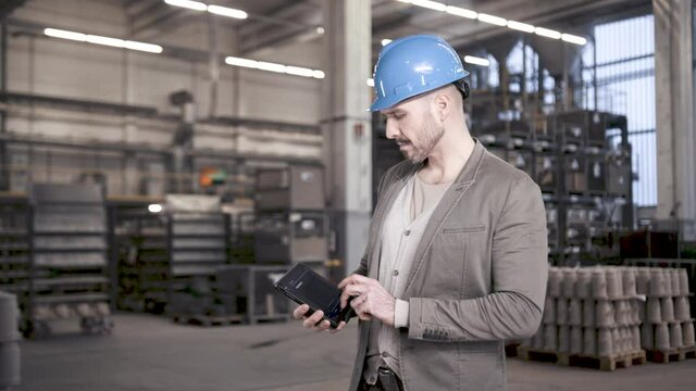 Proud engineer using tablet computer in industrial plant for data analysis