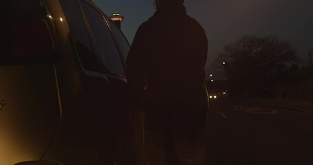Man approaches and enters parked truck on busy road, slow motion