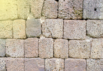 Ancient castle wall made of large stone, fair light.