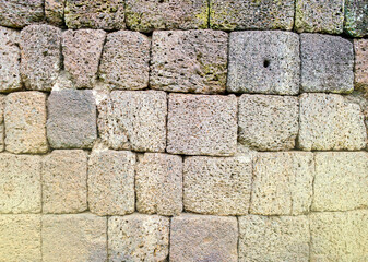 Ancient castle wall made of large stone, fair light.