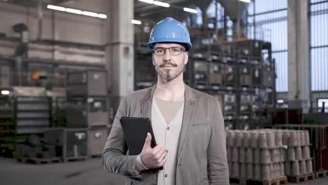 Proud engineer showing carrying tablet computer in industrial plant
