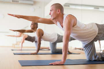 Fototapeta na wymiar Portrait of man practicing yoga lesson at group class, maintaining healthy lifestyle