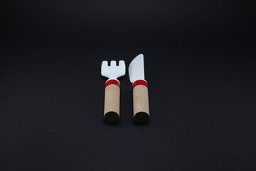 Wooden knife and fork, food icon. Black background