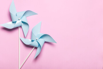 Blue paper spinners on light pink background. Kids toys colorful pinwheels on celebration party...