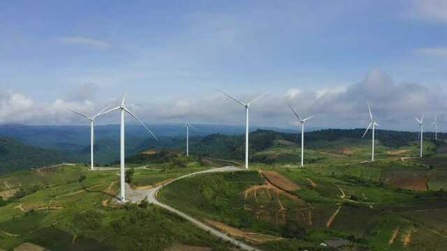 Aerial view of windmills rotating by the force of the wind for generating clean renewable energy for sustainable development in a green ecologic way on beautiful cloudy sky at highland.